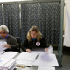 A woman sits reading ballots